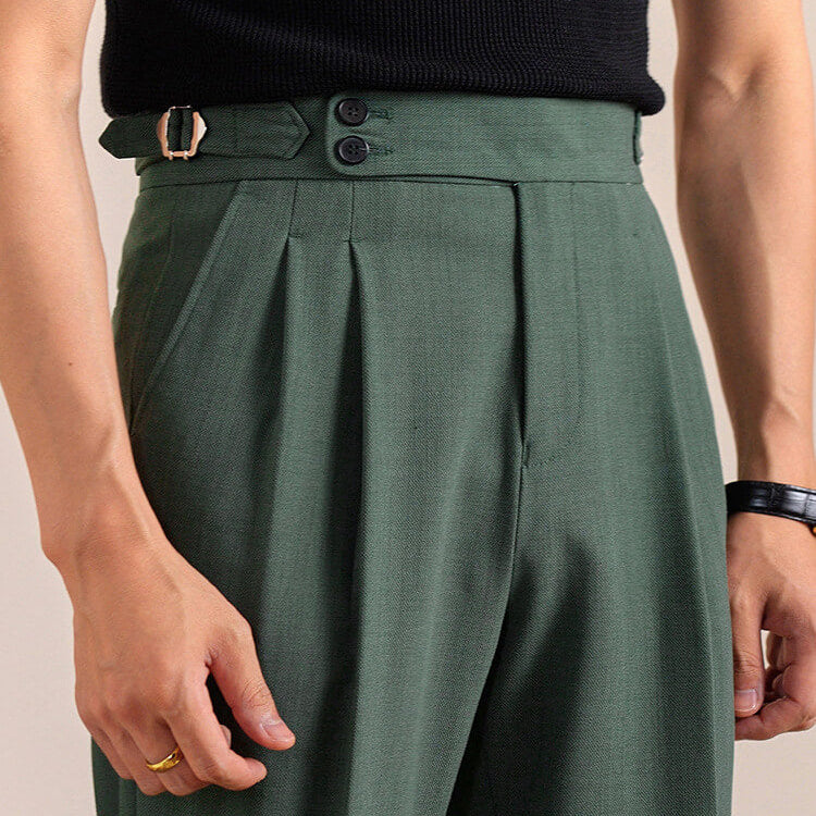 A close-up of a person wearing high-waisted olive green trousers with pleats,